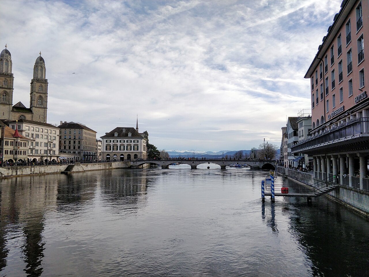 Vue du centre-ville de Zurich, avec l'église Grossmünster, la rivière Limmat, et, au loin, les Alpes suisses