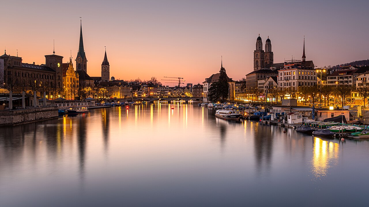 Long exposure shot of the old town of Zurich and the river Limmat taken from Quay Bridge. The image contains the three Churches Grossmünster, Fraumünster and Peterskirche.